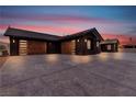 Contemporary single-story home with a dark exterior, tile roof, and a spacious concrete driveway at 6235 N Fort Apache Rd, Las Vegas, NV 89149