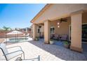 Covered outdoor patio with stylish seating, ceiling fan, and views of the pool area at 7252 Blowing Breeze Ave, Las Vegas, NV 89179