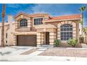 Charming home exterior featuring a two-car garage, red tile roof, an arched window and well-maintained landscaping at 8737 Autumn Valley Ave, Las Vegas, NV 89129