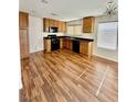 Well-lit kitchen featuring wood floors, modern appliances, wood cabinets, and a stylish light fixture at 12021 Spice Tree St, Las Vegas, NV 89183