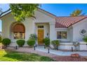 Close-up of the front entrance with a wooden door, an arched window, and desert landscaping at 9201 Yucca Blossom Dr, Las Vegas, NV 89134