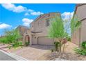 Two-story home with neutral stucco, paver driveway, and desert landscaping at 9947 Tucket Point Ct, Las Vegas, NV 89178