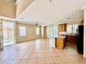 Spacious floorplan with tile floors, a ceiling fan, and kitchen with wooden cabinetry and black appliances at 5517 Overlook Valley St, North Las Vegas, NV 89081