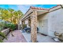 Charming covered back patio area with decorative stone pillars, an outdoor dining set, and sliding door access to the house at 2253 Van Gogh Dr, Henderson, NV 89074