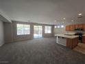 Open-concept living room features neutral carpet, natural light, and an adjacent kitchen at 7572 Coyote Cave Ave, Las Vegas, NV 89113