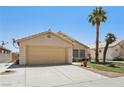 Charming single-story home featuring a two-car garage, desert landscaping and mature palm trees at 5580 Lonesome Biker Ln, Las Vegas, NV 89113