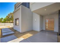 Modern home featuring a sleek front entrance with a wood door and a minimalist desert landscape at 6335 Westwind Rd, Las Vegas, NV 89118