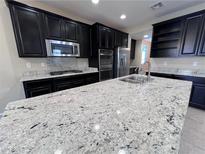 Modern kitchen with a large island, stainless steel appliances, and dark cabinets at 7421 Old Compton St, Las Vegas, NV 89166