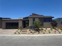 Modern single-story home with stone accents, a glass garage door, and desert landscaping in the front yard at 137 Tre Pietre St, Henderson, NV 89011