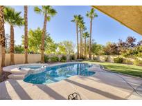 Inviting backyard pool and spa surrounded by lush landscaping and tall palm trees for a private oasis at 1002 Prestige Meadows Pl, Henderson, NV 89052