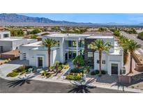 Contemporary home featuring a light exterior, manicured landscaping, and palm trees, set against a mountain backdrop at 9760 Solar Ave, Las Vegas, NV 89149