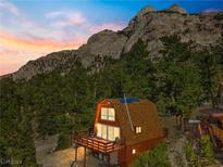 Charming cabin-style home with mountain views and a wooden deck, nestled among lush greenery at 2196 Via Dulcedo St, Mount Charleston, NV 89124
