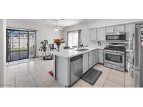Modern kitchen features stainless steel appliances, an island with sink, and sliding door access to backyard at 367 Lander Dr, Henderson, NV 89074