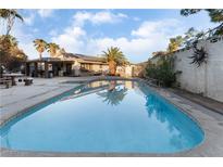 A beautiful backyard pool reflects the sky and palm trees, perfect for relaxing and entertaining at 2240 Horse Creek Cir, Henderson, NV 89014