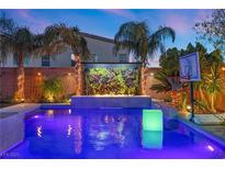 Stunning pool with a waterfall feature and landscape lighting at 8620 Grove Mill Ct, Las Vegas, NV 89139