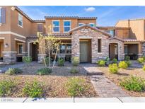 Charming two-story townhouse showcasing a stone facade, well-manicured landscaping, and a welcoming front porch at 3237 Pergusa Dr # 0, Henderson, NV 89044