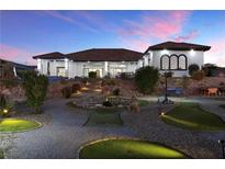 Stunning backyard with a custom putting green, water feature, and landscaped grounds at twilight at 162 S Naples St, Henderson, NV 89015