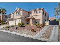 Stucco two-story home with a well-manicured rock garden, mature trees and a two-car garage and black iron driveway gate at 7310 Heggie Ave, Las Vegas, NV 89131