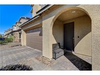 Inviting front entrance featuring an arched doorway, neutral stucco exterior, and a cozy bench at 2796 Sipe Springs St, Las Vegas, NV 89142