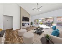 Bright living room with wood floors, fireplace, ceiling fan, and a sliding glass door to the backyard at 8517 Bayland Dr, Las Vegas, NV 89134