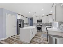 Modern kitchen with white cabinets, stainless steel appliances, and island at 8774 Libertyvale Dr, Las Vegas, NV 89123