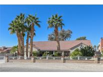 Charming single-story home featuring lush palm trees, a brick-and-wrought-iron fence, and a well-manicured front yard at 485 Sari Dr, Las Vegas, NV 89110