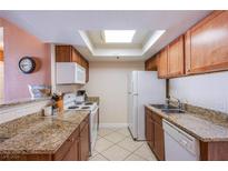 Efficient kitchen featuring granite countertops, wooden cabinetry, and stainless steel appliances under a skylight at 4200 S Valley View Blvd # 3030, Las Vegas, NV 89103