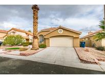 Tan house with a two-car garage and desert landscaping at 7812 Desert Candle Way, Las Vegas, NV 89128