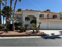 Two-story house with tile roof, three-car garage, and landscaped yard at 6365 Black Swan Ln, Las Vegas, NV 89118