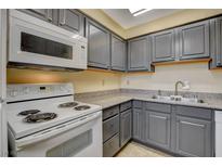 Cozy kitchen with gray cabinets, laminate countertops, and white appliances at 5301 River Glen Dr # 210, Las Vegas, NV 89103