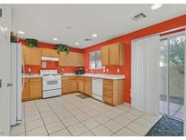 Bright kitchen features light wood cabinets, white appliances, and orange walls at 6058 Ambleshire Ave, Las Vegas, NV 89139