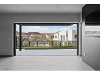 Open living space with tiled floors and sliding doors leading to a patio with views of the community and mountains at 42 Promenade Isle Ln, Henderson, NV 89011