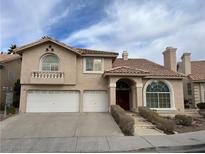 Tan two-story house with three-car garage, arched entryway, and landscaped walkway at 2412 Eagleridge Dr, Henderson, NV 89074