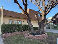 Tan two-story home with brown roof, mature trees, and landscaped yard at 3719 Colonial Dr, Las Vegas, NV 89121