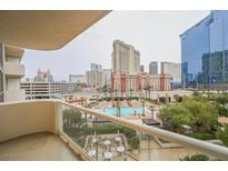 A balcony overlooking a swimming pool, palm trees, and the Las Vegas Strip, offering a serene outdoor space at 135 E Harmon Ave # 407, Las Vegas, NV 89109