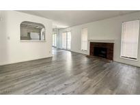 Open living room with a brick fireplace, grey laminate flooring, and natural lighting at 6137 W Oakey Blvd # A, Las Vegas, NV 89146