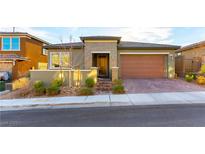 Single-story home with green exterior, brick driveway, and two-car garage at 881 Haven Oaks Pl, Las Vegas, NV 89138