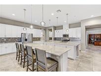 Bright open kitchen with white cabinets, stainless steel appliances, and large granite island at 480 Heritage Bridge Ave, Henderson, NV 89011