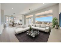 Bright living room featuring modern white sofa, large windows, and an open floor plan that connect to the dining area at 2904 Bow Bridge Dr, Las Vegas, NV 89134