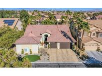 Single-story home with a tile roof, two-car garage, and landscaped yard; city views in background at 5378 Pendini Point Ct, Las Vegas, NV 89141