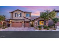 Two-story house with tan siding, brown garage doors, and stone accents at 7563 Saguaro Cactus Ave, Las Vegas, NV 89178