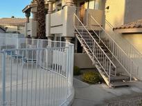 Exterior view of building, showing stairs, patio, and pool area with lounge chairs at 1013 Falconhead Ln # 101, Las Vegas, NV 89128