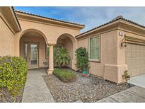 Inviting entryway with arched entry, mature shrubs, and a paved walkway at 5124 Pensier St, Las Vegas, NV 89135