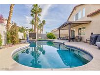 Inviting kidney-shaped pool with covered patio and lush landscaping at 9542 Gainey Ranch Ave, Las Vegas, NV 89147