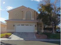 Two-story house with tan exterior, white garage door, and landscaping at 2525 Huber Heights Dr, Las Vegas, NV 89128