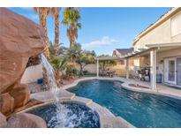 Inviting backyard oasis featuring a sparkling pool, waterfall, and covered patio at 8529 Copper Knoll Ave, Las Vegas, NV 89129