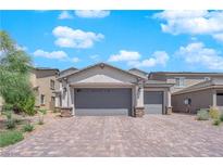 Two-story house with gray exterior, paver driveway, and landscaping at 1606 Dire Wolf Ave, North Las Vegas, NV 89084