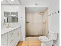 Modern bathroom with white cabinets, gold fixtures, and a walk-in shower at 2620 San Martin Ct, Las Vegas, NV 89121