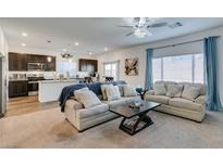 Open-concept living room featuring plush seating, a modern ceiling fan, and an adjacent kitchen area at 10467 Joaquin Fire St, Las Vegas, NV 89141