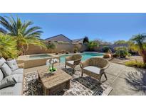 Inviting backyard oasis featuring a sparkling pool, spa, and cozy patio seating under the sunny sky at 2470 Lothian St, Henderson, NV 89044